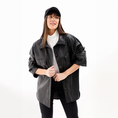 Modelo usando una chaqueta Zenda negra, con un diseño elegante y moderno, combinada con una camiseta blanca y una gorra negra.