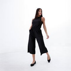 Modelo luciendo una musculosa negra con pantalones amplios en un fondo blanco.