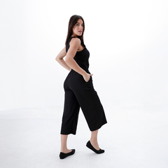Mujer posando con pantalones capri negros y blusa sin mangas, mostrando un estilo moderno y cómodo.