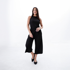Mujer posando con un conjunto de pantalones capri negros y una blusa sin mangas negra.