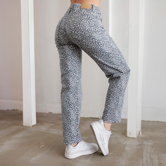 Pantalón de mezclilla gris con estampado de leopardo, visto desde atrás, combinado con zapatillas blancas.