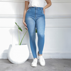 Jean celeste de corte ajustado, combinado con una camiseta blanca y zapatillas blancas, junto a una planta en una maceta blanca.