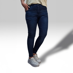 Jean Dixy en denim oscuro, ajustado, con una modelo de pie usando zapatillas blancas.