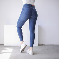 Jean Frida ajustado de denim azul, visto desde atrás con una modelo usando zapatillas blancas.