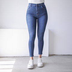 Jean Frida de tiro alto en denim azul, ajustado a la figura, combinado con zapatillas blancas.