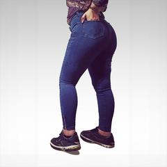 Jeans ajustados de color azul, vistos desde el lado, con un diseño moderno y detalles en la parte trasera.