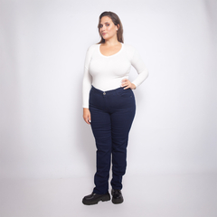Modelo usando jeans Memphis de color azul oscuro, combinados con una blusa blanca de manga larga y botas negras.