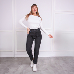 Mujer posando con jeans MOM de color negro y camiseta blanca en un fondo claro.