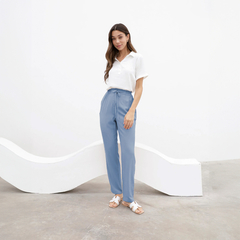 Pantalón Chenoa de color azul claro, con una blusa blanca, posando en un entorno minimalista.