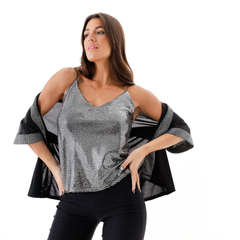 Musculosa Piper de color plateado con detalles brillantes, combinada con una chaqueta negra, vista frontal, modelo posando con confianza.