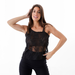 Musculosa Astradea negra de encaje, con tirantes finos y diseño transparente, presentada por una modelo en un fondo blanco.
