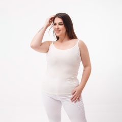 Musculosa básica blanca de tirantes, modelo sonriente con cabello suelto, en un fondo blanco.
