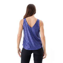 Musculosa Casiopea de color azul con brillos, vista trasera, combinada con pantalones negros.