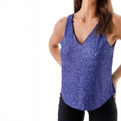 Musculosa Casiopea de color púrpura con brillos, escote en V y tirantes anchos, combinada con pantalones oscuros.