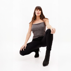 Mujer posando con una blusa sin mangas y pantalones negros, en un fondo blanco.