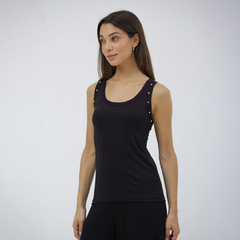 Musculosa negra sin mangas con detalles de strass en los hombros, modelo de mujer de pie con fondo neutro.