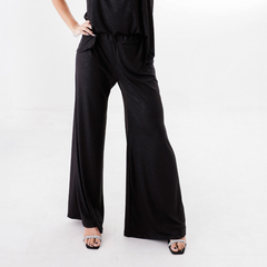 Pantalones palazzo negros con brillo, con bolsillos y cintura elástica, modelo de mujer en un fondo blanco.