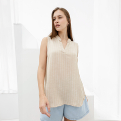 Musculosa Nova de color beige con rayas, sin mangas, con cuello tipo solapa, combinada con pantalones cortos de mezclilla.