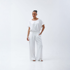 Mujer posando con un conjunto blanco de pantalones palazzo y blusa de manga corta.