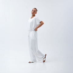 Modelo luciendo un conjunto Palazzo Benja de color blanco, con una blusa suelta y pantalones amplios, en un fondo blanco.