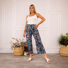 Pantalones Palazzo Daia con estampado floral en tonos azul y rosa, modelo de pie en un ambiente moderno.