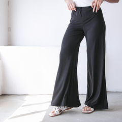 Pantalones palazzo negros, elegantes y cómodos, con una modelo que muestra el diseño y la caída del tejido.
