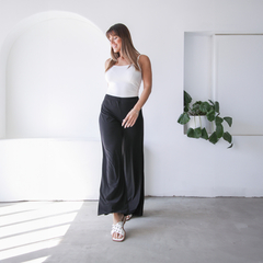 Pantalón palazzo negro de la colección Elhas, combinado con una blusa blanca, presentado en un ambiente moderno.