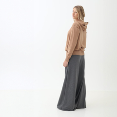 Mujer de pie de perfil vistiendo un conjunto con un pantalón palazzo gris y un hoodie beige.