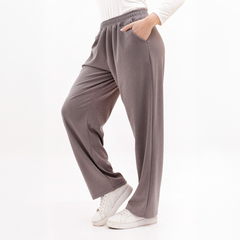 Pantalones grises de mujer con corte amplio y bolsillos, combinados con una camiseta de manga larga blanca y zapatillas blancas.