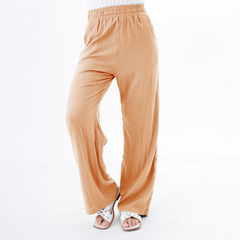 Pantalones palazzo de color melocotón con cintura elástica, combinados con sandalias blancas.