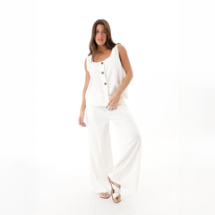 Mujer posando con un conjunto de pantalones palazzo y blusa blanca, mostrando un estilo moderno y elegante.