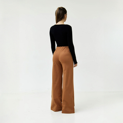 Pantalones palazzo de color marrón con una blusa negra, vista desde atrás.