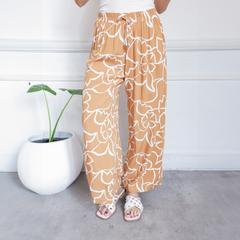 Pantalones Palazzo Vivi de color naranja con estampado floral blanco, combinados con sandalias blancas.