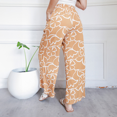 Pantalones Palazzo Vivi de color naranja claro con estampado de flores blancas, vistos desde atrás.