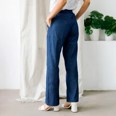 Pantalón Lorena en denim oscuro visto desde atrás, con una modelo usando una blusa blanca y sandalias.