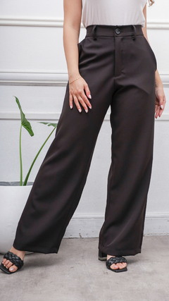 Pantalón Turín de color negro, con un corte elegante y amplio, presentado por una mujer que lleva un top blanco y sandalias negras.