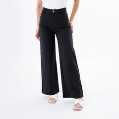 Pantalón Vivian de color negro con corte amplio, combinado con una camiseta blanca y sandalias claras.