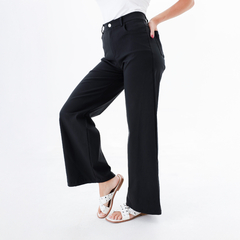 Pantalón Vivian de color negro con corte amplio, combinado con sandalias blancas.