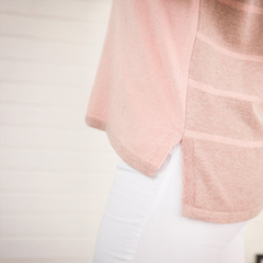 Sweater de color rosa con detalles en la parte lateral, visto desde un lado, sobre fondo claro.