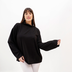 Polera lanilla negra de manga larga, con diseño holgado, usada por una mujer en un fondo blanco.