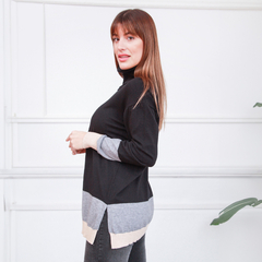 Polera Ligia de color negro con detalles en gris y beige, modelo de perfil en un ambiente luminoso.