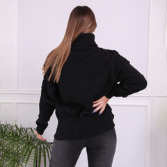 Vista posterior de una mujer usando una polera negra con cuello alto, destacando el diseño y el material del suéter.