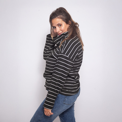 Modelo usando una polera a rayas negra y blanca, con un diseño moderno y cómodo.