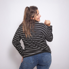 Modelo usando una polera Zafira de rayas negras y blancas, vista desde atrás.