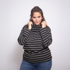 Modelo usando una polera de rayas negras y blancas, con cuello alto, posando y sonriendo.