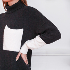 Polerón negro de mujer con cuello alto y bolsillo blanco en el pecho, ideal para el invierno.