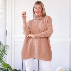 Polerón Zoe de color beige con cuello alto y bolsillos, usado por una mujer en un entorno luminoso.