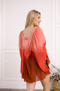 Poncho Amaru en tonos coral, con detalles de encaje en la espalda, modelo femenino posando de perfil.