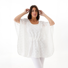 Poncho Magda blanco, de diseño ligero y fluido, con una textura calada, modelado por una mujer que lo lleva con elegancia.