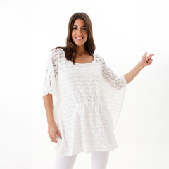 Poncho Magda de color blanco, con diseño de calado y mangas anchas, modelo femenino posando y sonriendo.